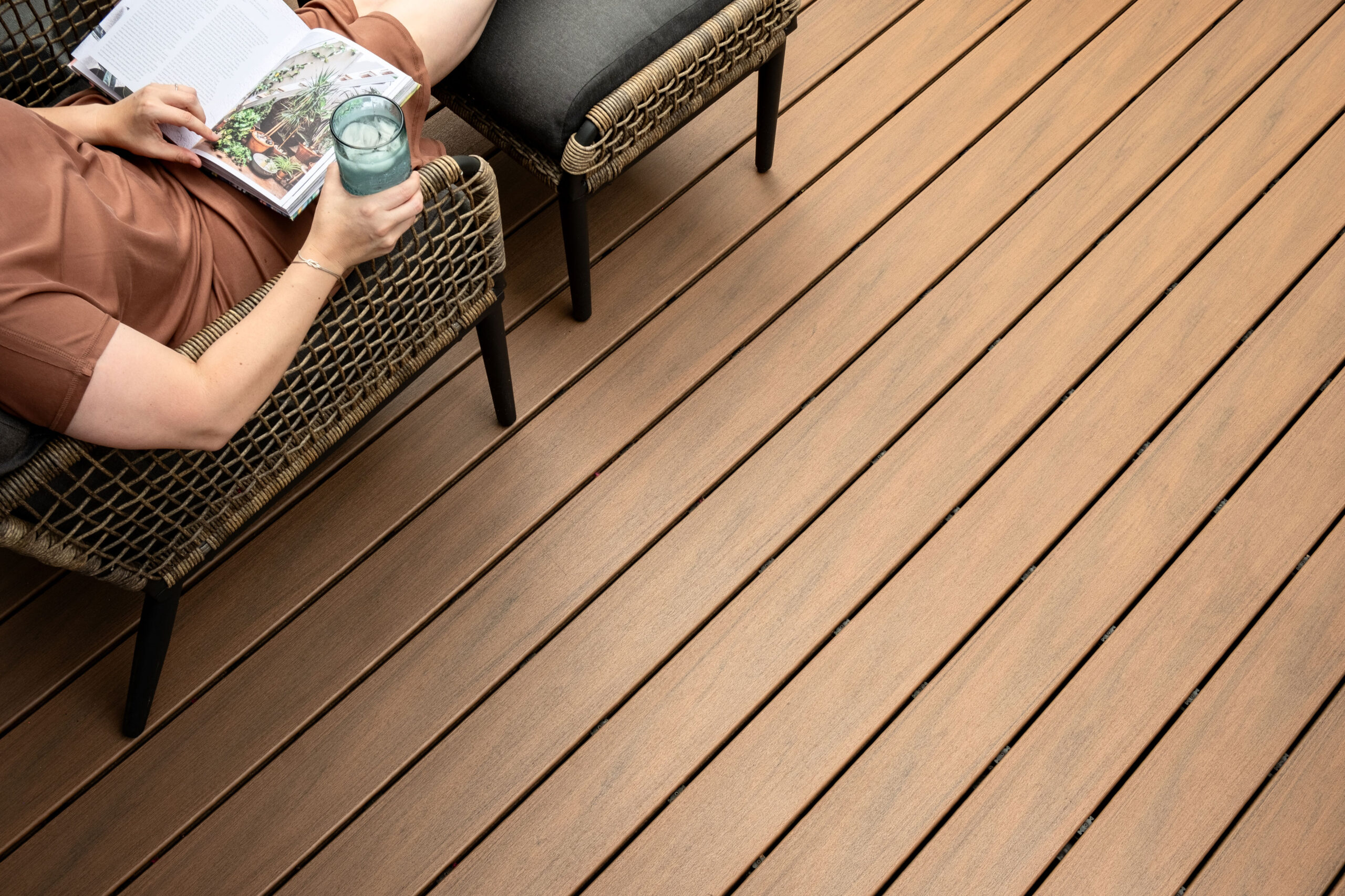 Deski tarasowe Trex Transcend Lineage, fotel oraz wypoczywająca osoba na tarasie.