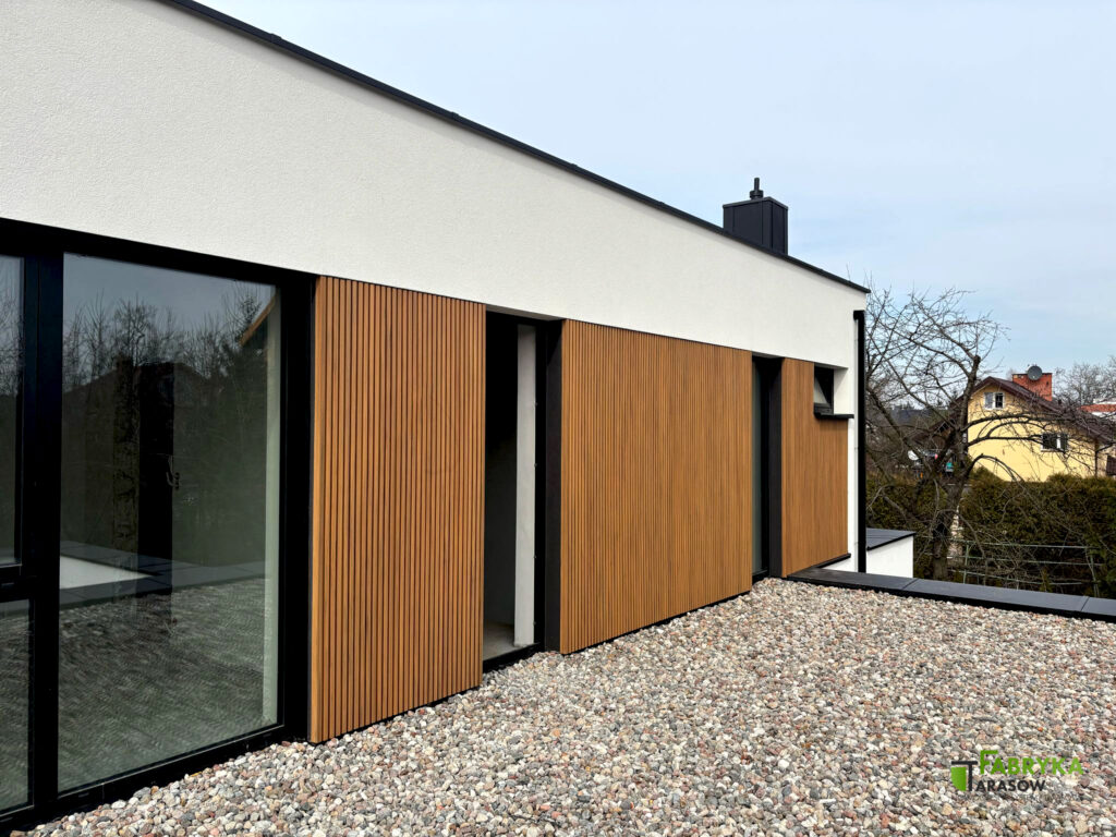 Lamele elewacyjne zastosowane na ścianie domu w połączeniu z dużymi oknami o czarnym obramowaniu - realizacja Fabryki Tarasów.