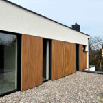 Lamele elewacyjne zastosowane na ścianie domu w połączeniu z dużymi oknami o czarnym obramowaniu - realizacja Fabryki Tarasów.