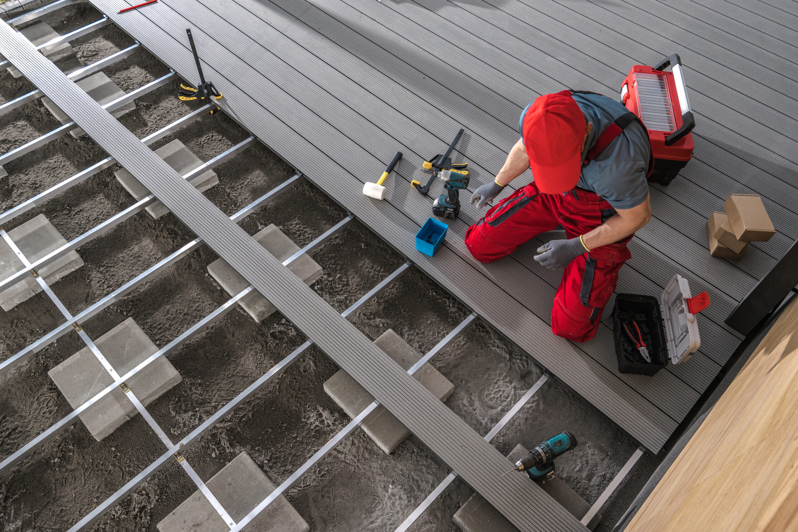 Specjalista pracujący nad montażem tarasu z desek kompozytowych na bloczkach betonowych.