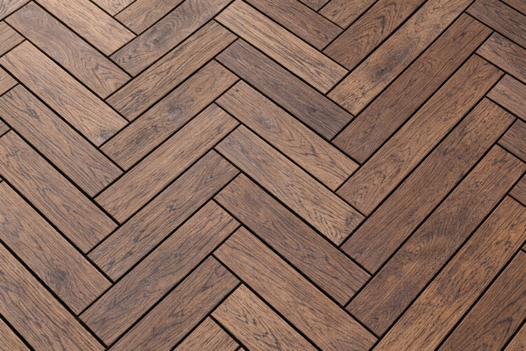 Zbliżenie na ułożenie desek tarasowych w wąską jodełkę.